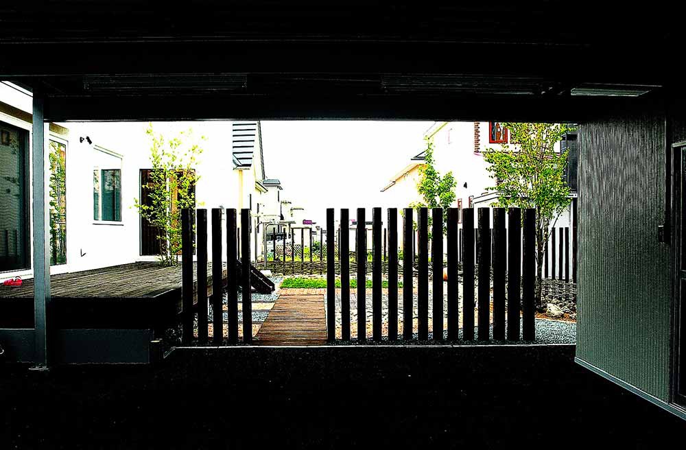 道路からは枕木のブラインド越しに見え隠れするセミ・クローズドガーデン・テラス部分。実用の部分と魅せる空間とをナチュラルな自然石ボーダーでつなぐ。