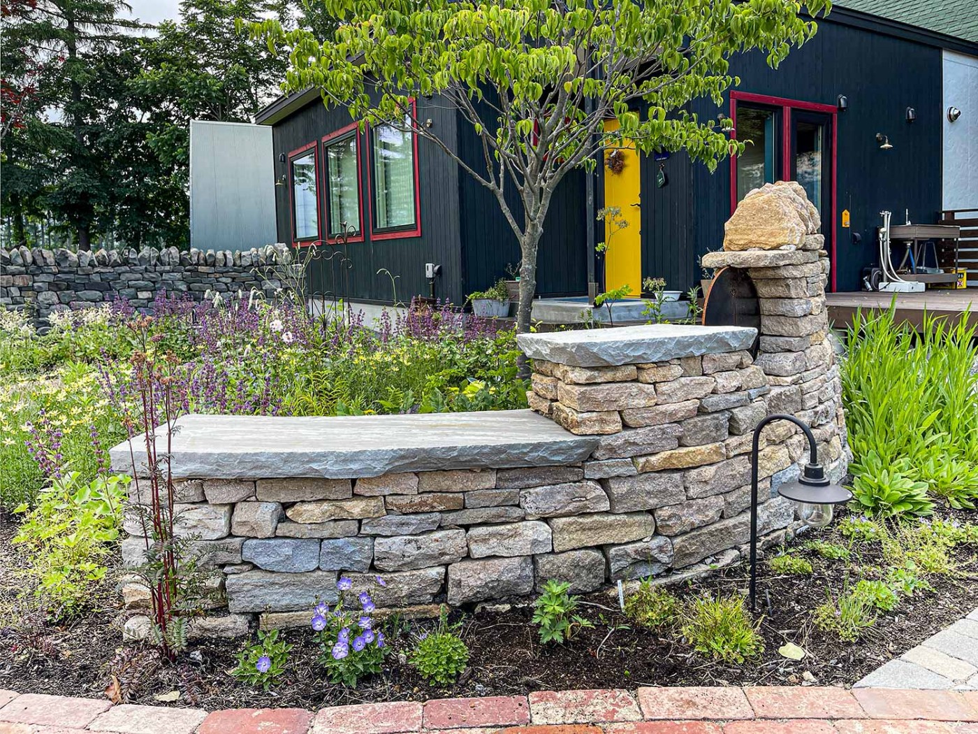 エントランス正面のサインと石積み。 ここはワンちゃん同伴可能なカフェなので、ここに愛犬を座らせて写真に収める姿を幾度となく見かけています。 微笑ましい限りです。 外周のダークトーンの石積みに対して明るいトーンの石積みになっています。北見の北黄石(ほっこうせき)を使用してモルタルなどを使わないドライストーンウォーリング技法で積み上げられています。見事です。