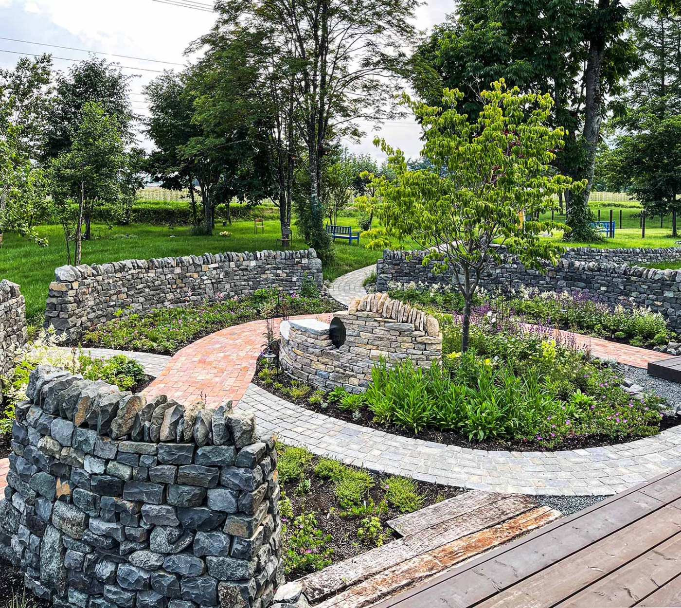 ウォールを過ぎてのエントランスアプローチ。 舗装の素材はニ種類で絡み合うメインとサブアプローチのコントラストで景観のアクセントとしています。 宿根草はまだもう少しですね。