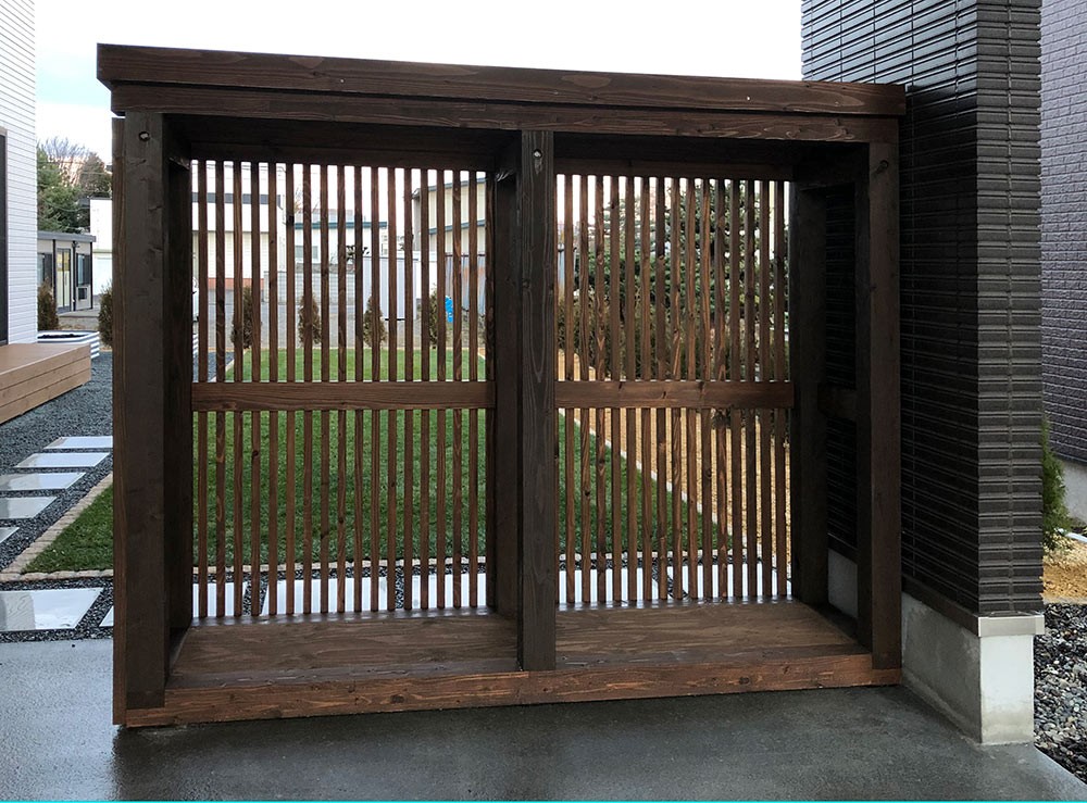 格子を背面に用いた薪小屋。