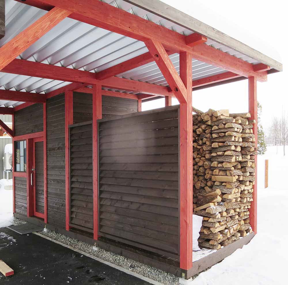 カーポートに併設した物置と薪小屋の景観。仕切り板はルーバー形状。